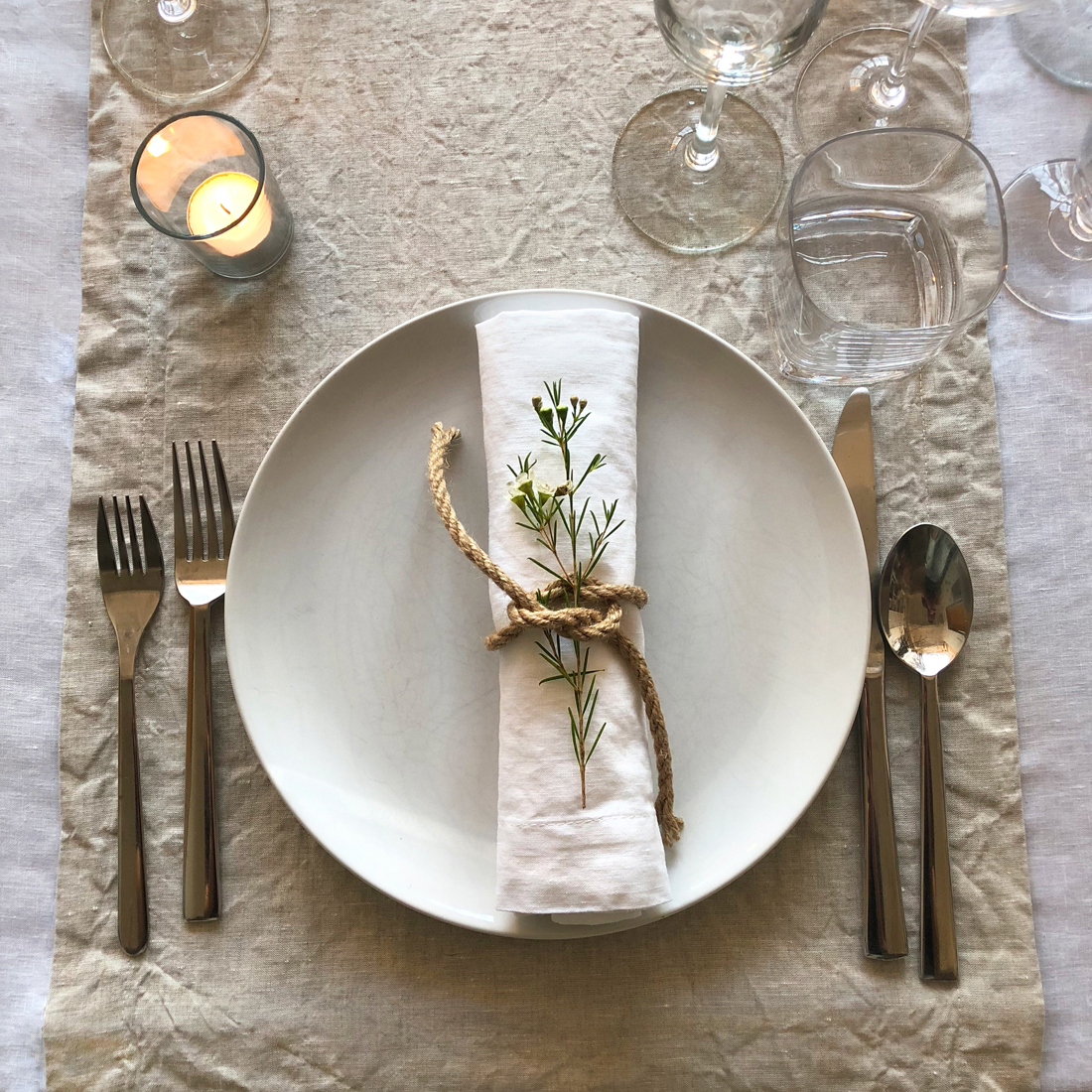 Scandinavian dinner party layering a white linen tablecloth with natural flax linen table runners and white linen napkins